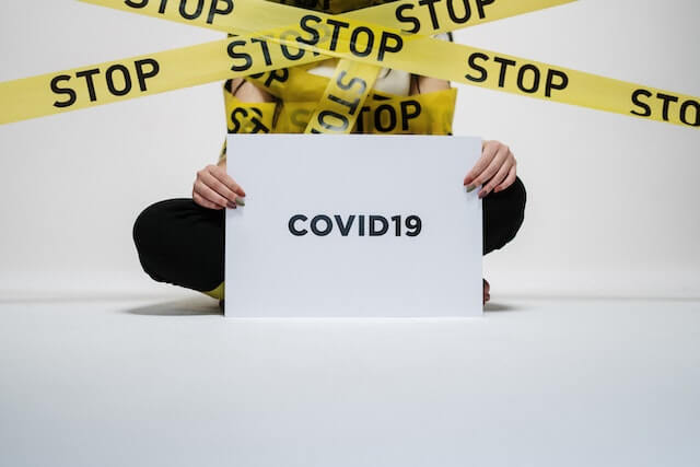 cinta de seguridad y una persona con un cartel de que dice COVID-19