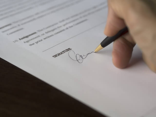 una mano firmando un documento de Co-firmante
